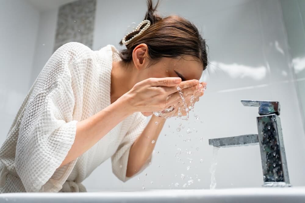 a woman wahsing her face in the morning
